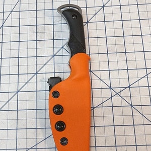 May include: A bright orange knife sheath with black snaps and a black knife with a black handle.