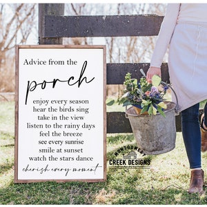 May include: A white wooden sign with black text that reads "Advice from the porch" and a list of things to enjoy on a porch, such as "enjoy every season", "hear the birds sing", "take in the view", "listen to the rainy days", "feel the breeze", "see every sunrise", "smile at sunset", "watch the stars dance", and "cherish every moment". The sign is hanging on a wooden fence.