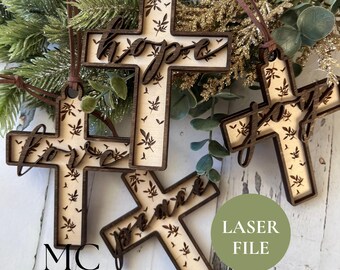May include: Wooden cross ornaments with the words "hope", "love", "joy", and "peace" cut out. The crosses have a light wood center with a leaf pattern and a dark wood border. Each ornament has a brown leather cord for hanging.