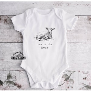 May include: White baby onesie with a black and white illustration of a lamb and the text "new to the flock".