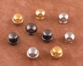 Puede incluir: Surtido de diez botones de metal en forma de cúpula en oro, plata y negro.