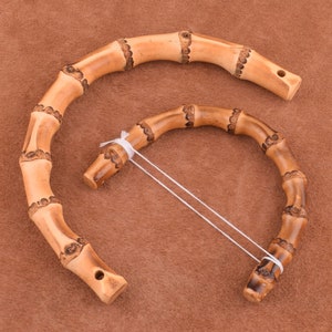 May include: Two brown bamboo handles with a white string connecting them. The handles are made of natural bamboo and have a smooth, polished finish.
