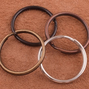 May include: Four key rings in different sizes and colors. The key rings are made of metal and are silver, black, and copper.