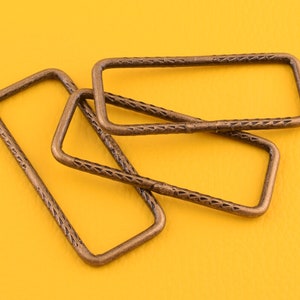 May include: Three antique gold-toned metal rectangular rings with a textured surface.