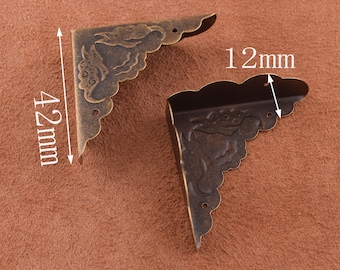 Può includere: Due protezioni per angoli in ottone antico con un motivo floreale decorativo. Ogni protezione misura 10,7 cm per 3 cm.