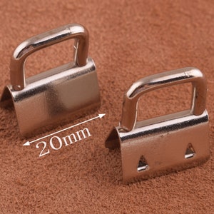 May include: Two silver metal D-ring buckles, each with a 20mm opening. The buckles are designed for attaching straps or belts to leather goods.