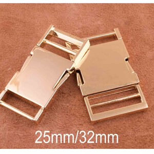 May include: Two gold-colored metal belt buckle clasps, one with a single slider and the other with a double slider. The clasps are 25mm by 32mm.