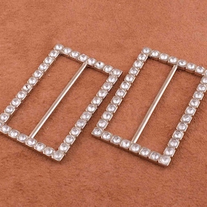 May include: Two silver-toned rectangular belt buckles with clear rhinestone embellishments.