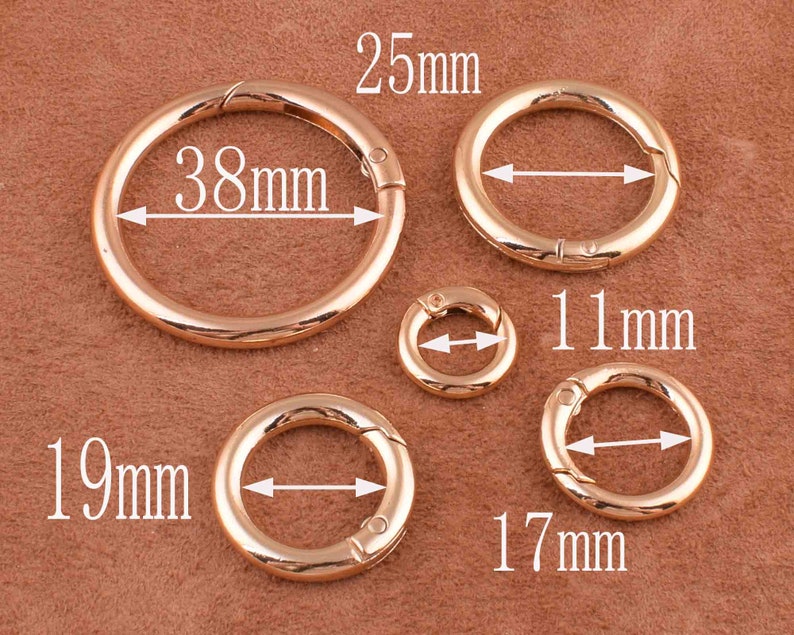 May include: Five gold-toned metal key rings of different sizes. The largest ring measures 38 mm in diameter, the next largest measures 25 mm, the next measures 19 mm, the next measures 17 mm, and the smallest measures 11 mm.
