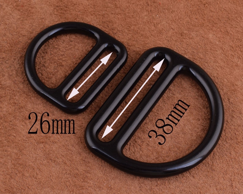 Peut inclure: Deux anneaux en D en m&eacute;tal noir avec une finition polie. Le plus grand anneau mesure 38 mm de diam&egrave;tre et le plus petit anneau mesure 26 mm de diam&egrave;tre.
