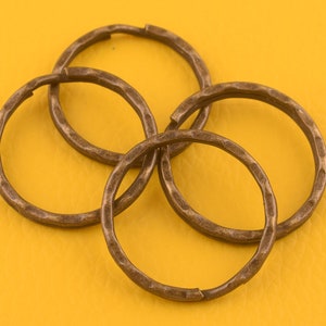 May include: Four antique gold-toned metal key rings. The key rings are interlocking and have a hammered texture.