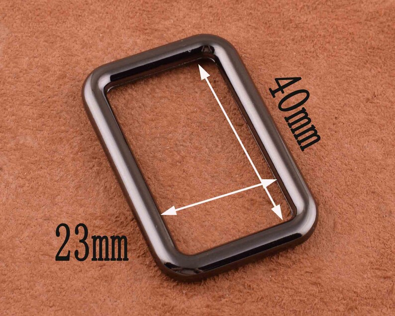Peut inclure: Un anneau rectangulaire en m&eacute;tal noir avec des coins arrondis. L'anneau mesure 40 mm sur 23 mm.