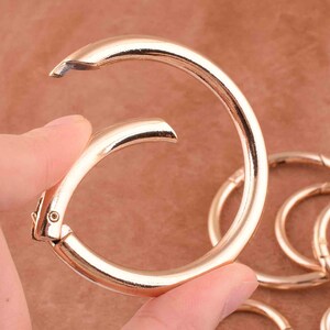 May include: A set of gold-toned metal key rings. The key rings are linked together and are made of a smooth, shiny metal.