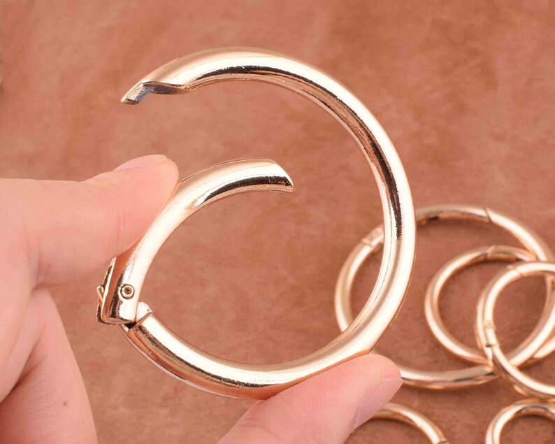 May include: A set of gold-toned metal key rings. The key rings are linked together and are made of a smooth, shiny metal.
