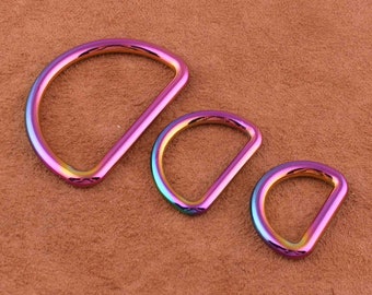 May include: Three iridescent metal D-rings in different sizes. The rings are a rainbow of colors, including pink, purple, blue, and green.