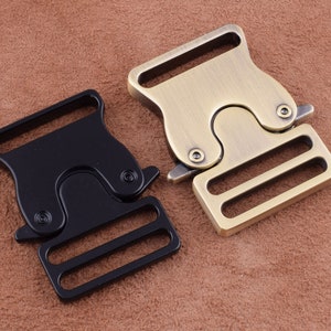 Puede incluir: Dos hebillas de liberación lateral de metal, una negra y una dorada. Ambas hebillas tienen un diseño de doble deslizador y son adecuadas para correas, bolsos u otros proyectos.