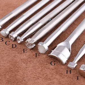May include: Nine silver metal leather craft tools with different shaped tips. The tips are labeled A through I.