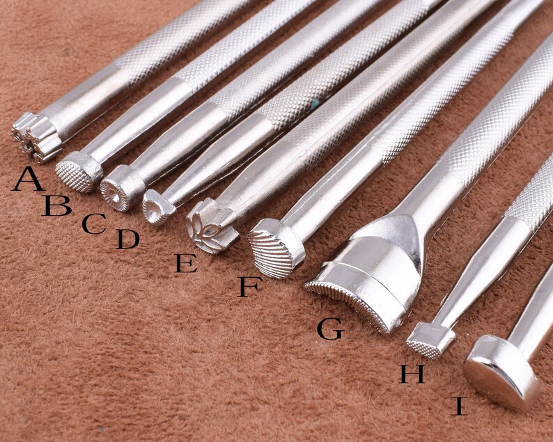 May include: Nine silver metal leather craft tools with different shaped tips. The tips are labeled A through I.