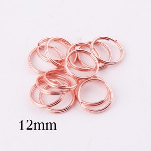 Pode incluir: Um monte de argolas de salto de ouro rosa de 12 mm. As argolas são de metal e são perfeitas para fazer joias ou artesanato.