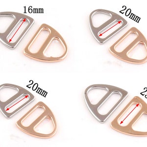 May include: Two sets of metal slider buckles, one set in silver and one set in rose gold. The buckles are shaped like a triangle with a rounded top and a rectangular opening in the centre. The buckles are available in three sizes: 16mm, 20mm, and 25mm.