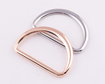 May include: Two metal D-rings, one silver and one rose gold. The rings are stacked on top of each other.