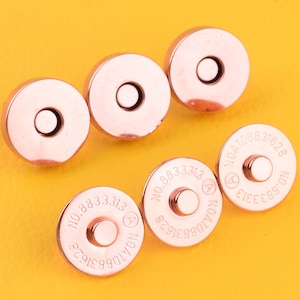 May include: Five rose gold magnetic snap closures with the text "NO.883313 NOATD8831628" engraved on each.