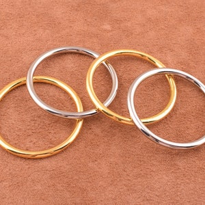 May include: Four interlocking metal rings, two gold and two silver, on a brown suede background.