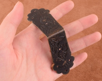 May include: Antique brass corner bracket with a decorative floral and bird design. The bracket has a scalloped edge and is about 2 inches wide.