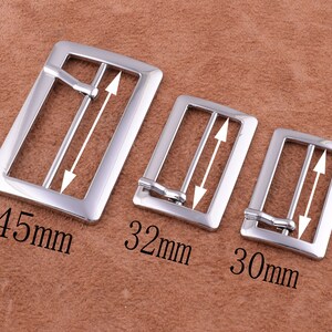 May include: Three silver metal belt buckles of different sizes. The largest buckle is 45 mm wide, the middle buckle is 32 mm wide, and the smallest buckle is 30 mm wide.