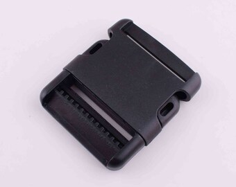 May include: Black plastic buckle with a side release mechanism. The buckle is designed for use with webbing or straps.