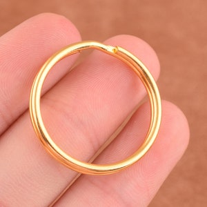 May include: A gold-colored metal key ring. The ring is round and has a smooth surface.