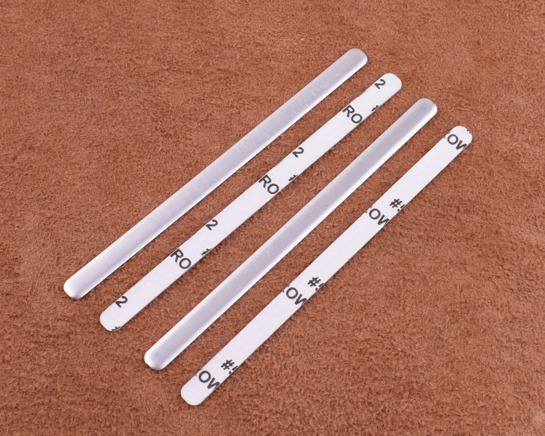May include: Four silver metal nose wire pieces for face masks. Each piece has a white label with the text "#5 OW" and "2 RO" printed on it.