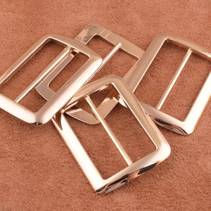 May include: Four gold-toned metal belt buckle closures. The buckles are rectangular with a smooth, polished finish.