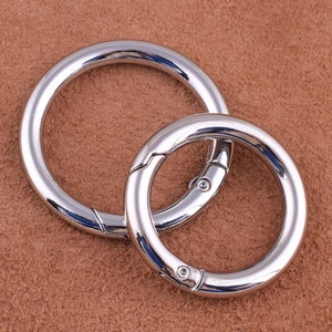 May include: Two silver metal key rings, one larger than the other, are linked together. The rings are smooth and shiny.