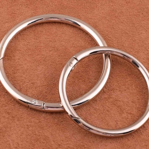 May include: Two silver metal key rings, one larger than the other, are linked together. The rings are smooth and shiny.