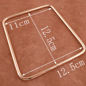 May include: Gold-toned metal handle with rounded edges. The handle measures 11 cm by 12.5 cm.