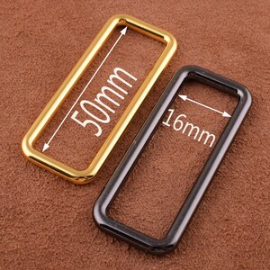 May include: Two metal belt loops, one gold and one black. The gold loop is 50mm wide and the black loop is 16mm wide.