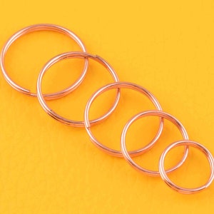 May include: Five different sized, rose gold coloured, metal key rings.