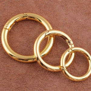May include: Three gold-colored metal key rings of different sizes. The rings are linked together.
