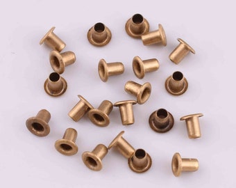 Op de afbeelding: Een verzameling van 20 gouden metalen oogjes. De oogjes zijn klein en hebben een ronde vorm met een verhoogde lip rond de rand. Ze worden vaak gebruikt voor knutselen en doe-het-zelfprojecten.
