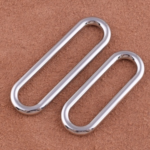 May include: Two silver oval-shaped metal rings. The rings are smooth and shiny.