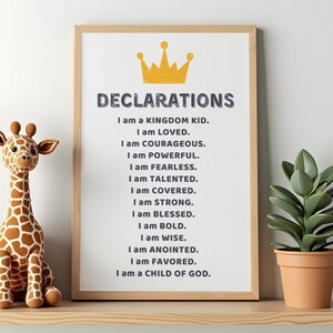 May include: A framed print with the word "DECLARATIONS" and a gold crown graphic. The print lists affirmations such as "I am LOVED" and "I am a CHILD OF GOD." A stuffed giraffe and potted plant are on the shelf.