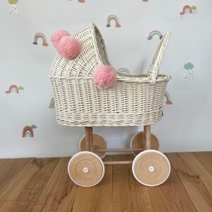 Wicker pram with bow, tall dolls pram, bow and bedding included. Cream/ off white pram with light pink pom-poms and bedding of your choice.