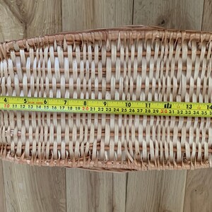 Pu&ograve; includere: Un cesto in vimini intrecciato di colore marrone chiaro con una finitura naturale. Il cesto &egrave; di forma ovale e misura 116,84 centimetri di lunghezza.