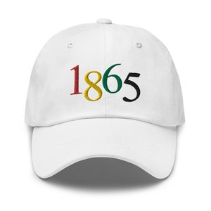 May include: White baseball cap with the year 1865 embroidered in red, yellow, green, and black.