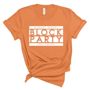 May include: Orange t-shirt with white text that reads "Market Street Block Party Inglewood"