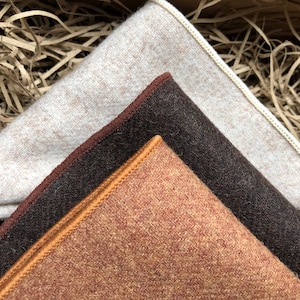 A photo of a set of three high quality wool pocket squares for men. The pocket squares are in shades of brown, camel and cream.