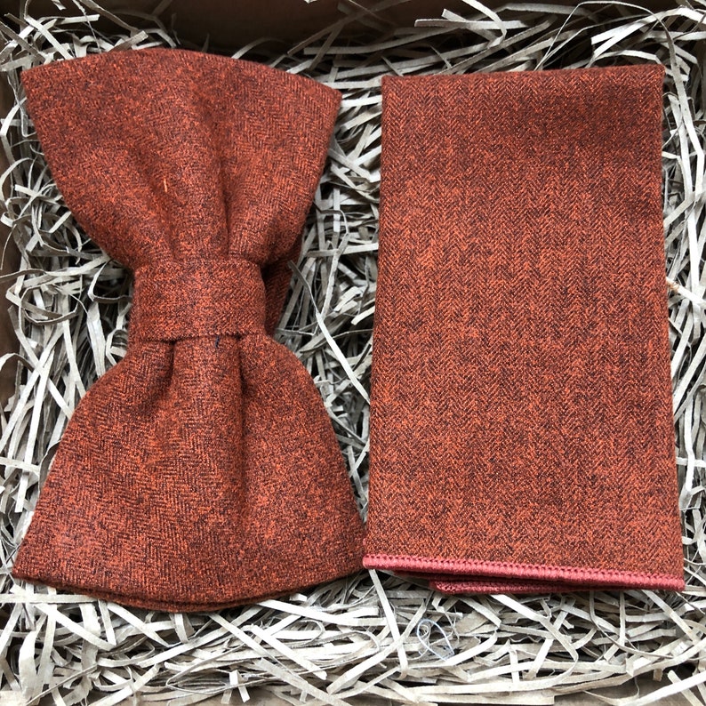 A photo of a burnt orange, cotton mens bow tie and a matching pocket square