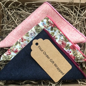 May include: Three pocket squares in a gift box. One is a solid pink, one is a floral print with pink and white flowers, and the other is a dark blue solid. The box has a brown paper tag that says "Your Order Gift Wrapped".