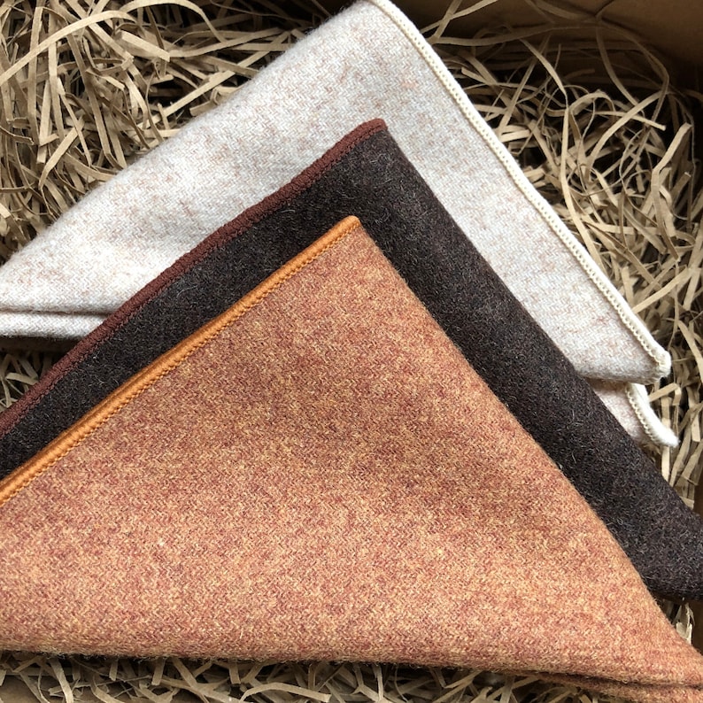 A photo of a set of three high quality wool pocket squares for men. The pocket squares are in shades of brown, camel and cream.